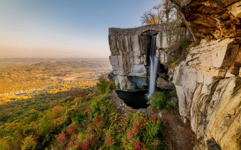 a waterfall off the cliffs of a forest