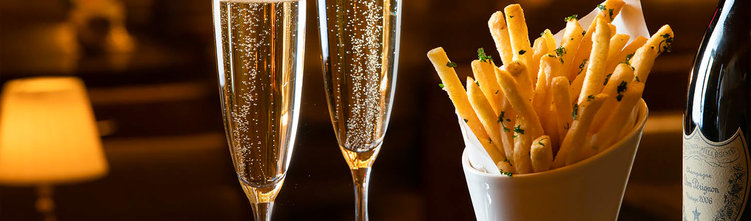 truffle fries next to two glasses and a bottle of champagne
