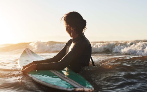 woman surfing at sunset 