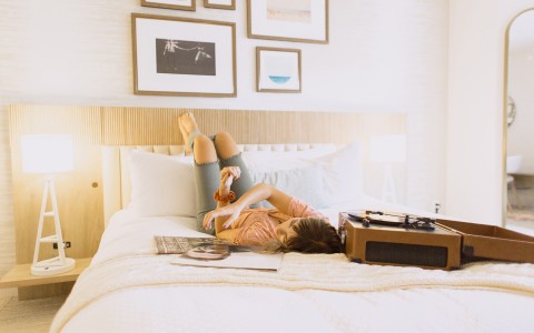woman laying in bed listening to a vinyl player