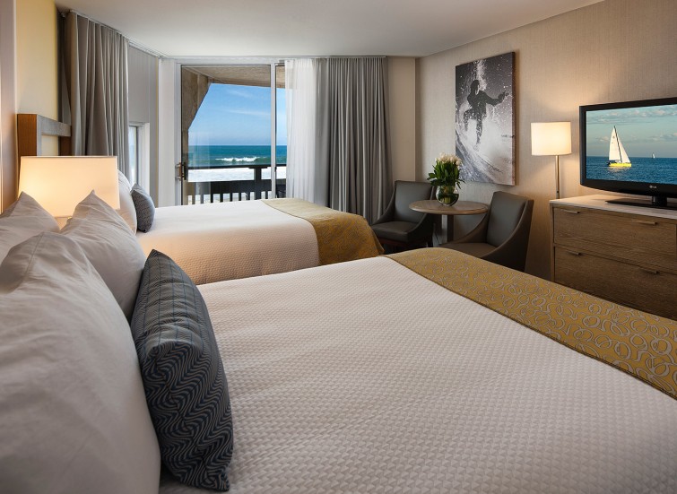 Hotel bedroom with 2 beds and a balcony facing the ocean