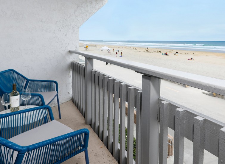 Hotel room balcony with 2 blue chairs facing the ocean