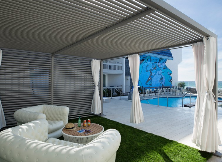 covered lounge area next to pool with patch of faux grass