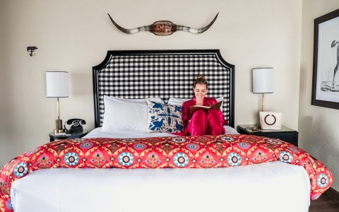 A woman reading on a colorful bed at Oceanpoint Ranch