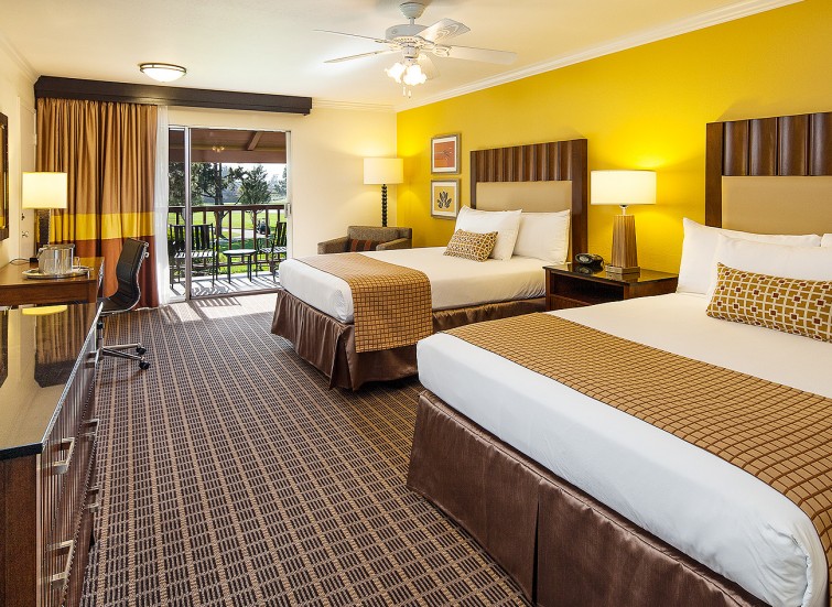 double beds in a hotel room with large balcony and a fireplace