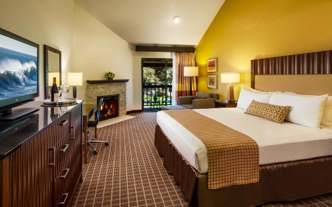 hotel suite with king bed and fireplace next to balcony
