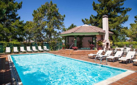 crystal blue pool with beach chairs next to clubhouse