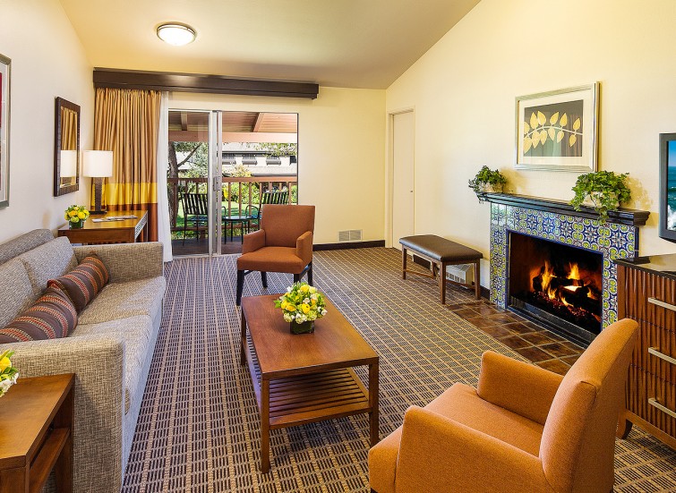 hotel suite living room with two small orange couches and one long brown sofa and a fireplace