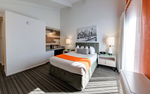 hotel bed with gray baseboard and headboard and orange throw blanket