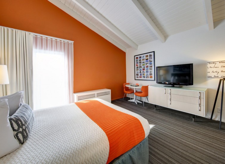 hotel room with bright orange accent wall and matching accent throw blanket
