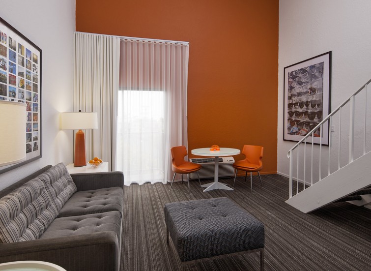 living room with gray sofa and foot rest and a bright orange wall