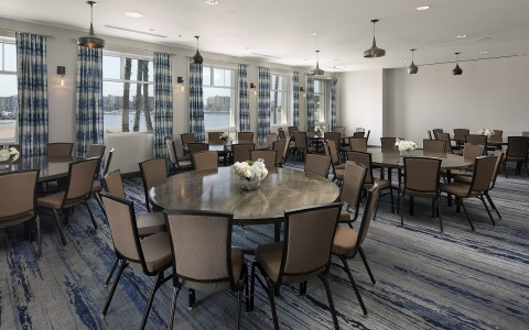 several indoor round tables with view of marina