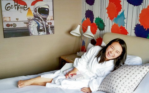 Woman laughing on hotel bed in a robe