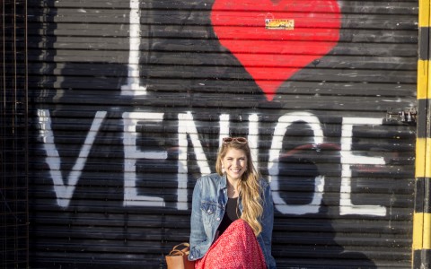 woman sitting in front of I heart Venice painting