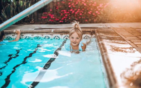 little blonde girl learning to swim in a pool