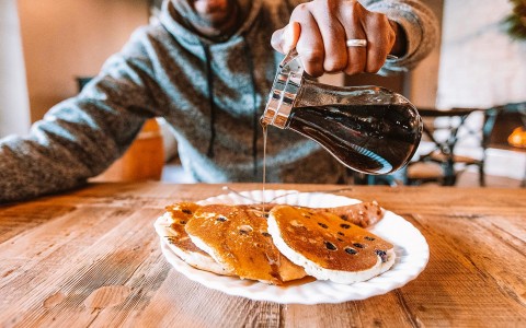pouring maple syrup on chocolate chip pancakes