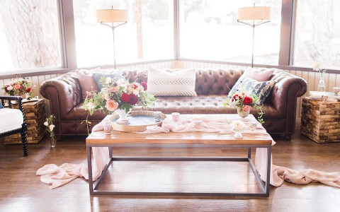 coffee table with beautiful bright flower vases and a silky pink tablerunner