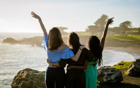 women posing in front of ocean