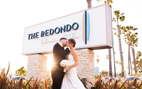 bride and groom kissing under the Redondo sign