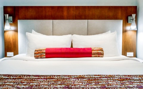 wood headboard with lamps and bed with red pillow