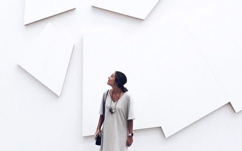 white wall with art in the background with a woman standing in front of it
