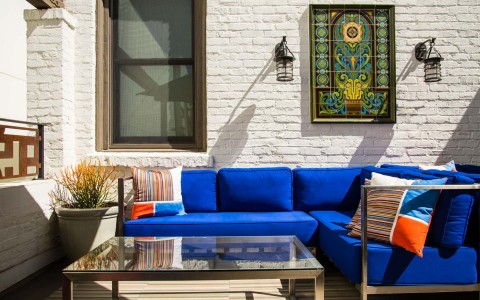 exterior living room with a sofa, table and a decorative paint
