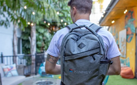 guy wearing a gray backpack with kinney logo on it