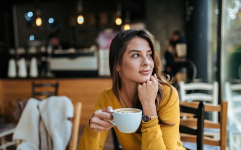 woman in yellow having a cup of coffee