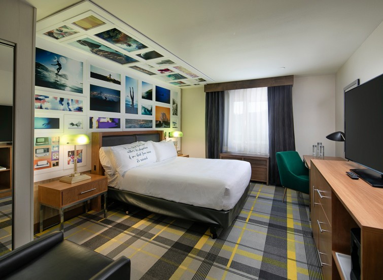 hotel room with gray plaid carpet floor and poster wall