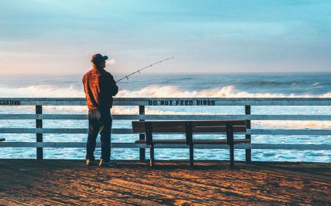 a man standing on the pier watching the waves