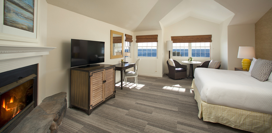 Hotel bedroom with view of ocean and fireplace