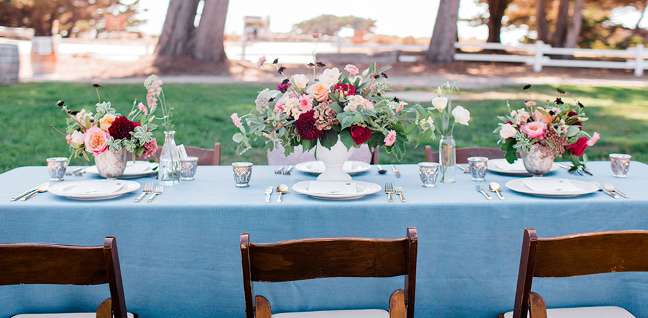 dining table set for an outdoor wedding with red and pink flowers