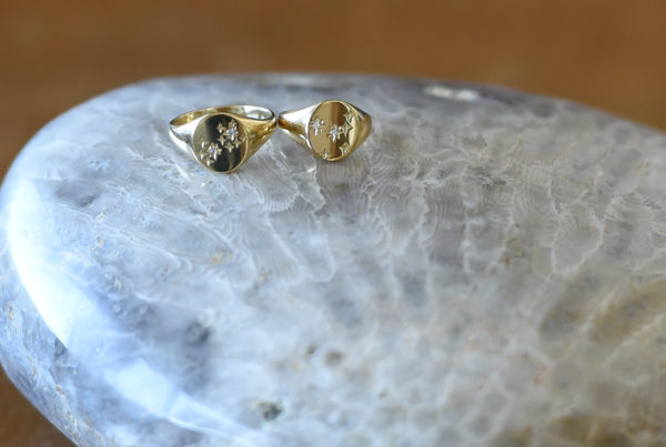 two gold rings with small diamonds on a small side table 