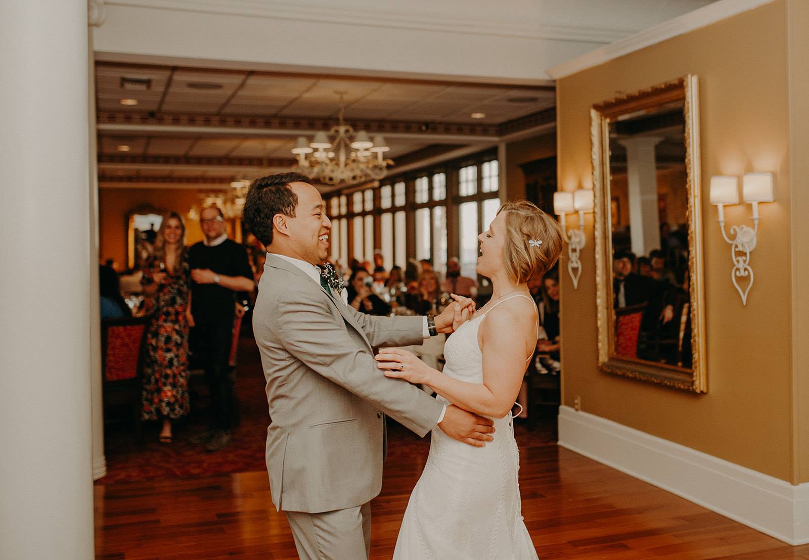 bride in long white dress dancing with the groom in the middle of a ballroom