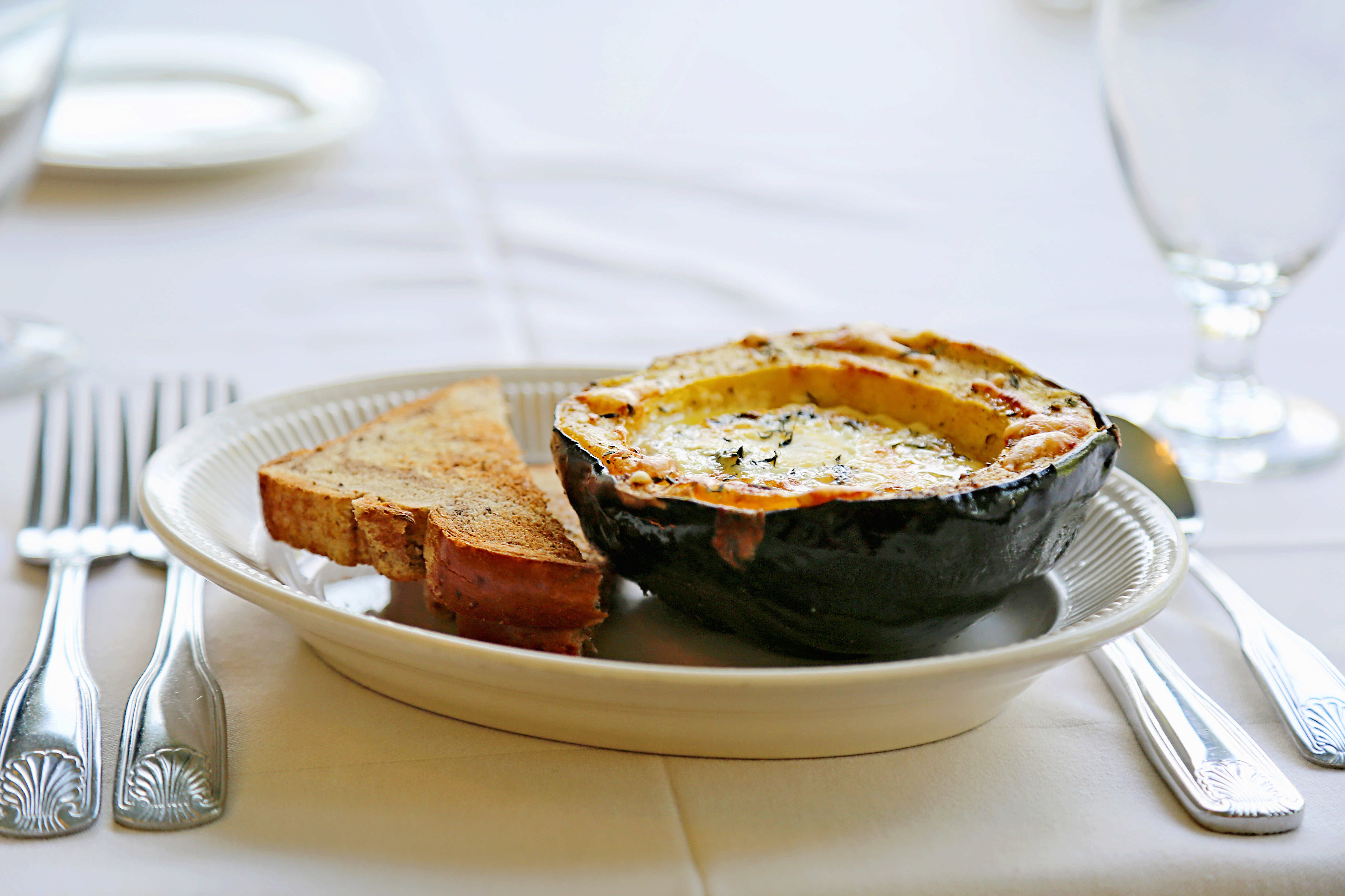 acorn squash on a white plate with silverware on the side