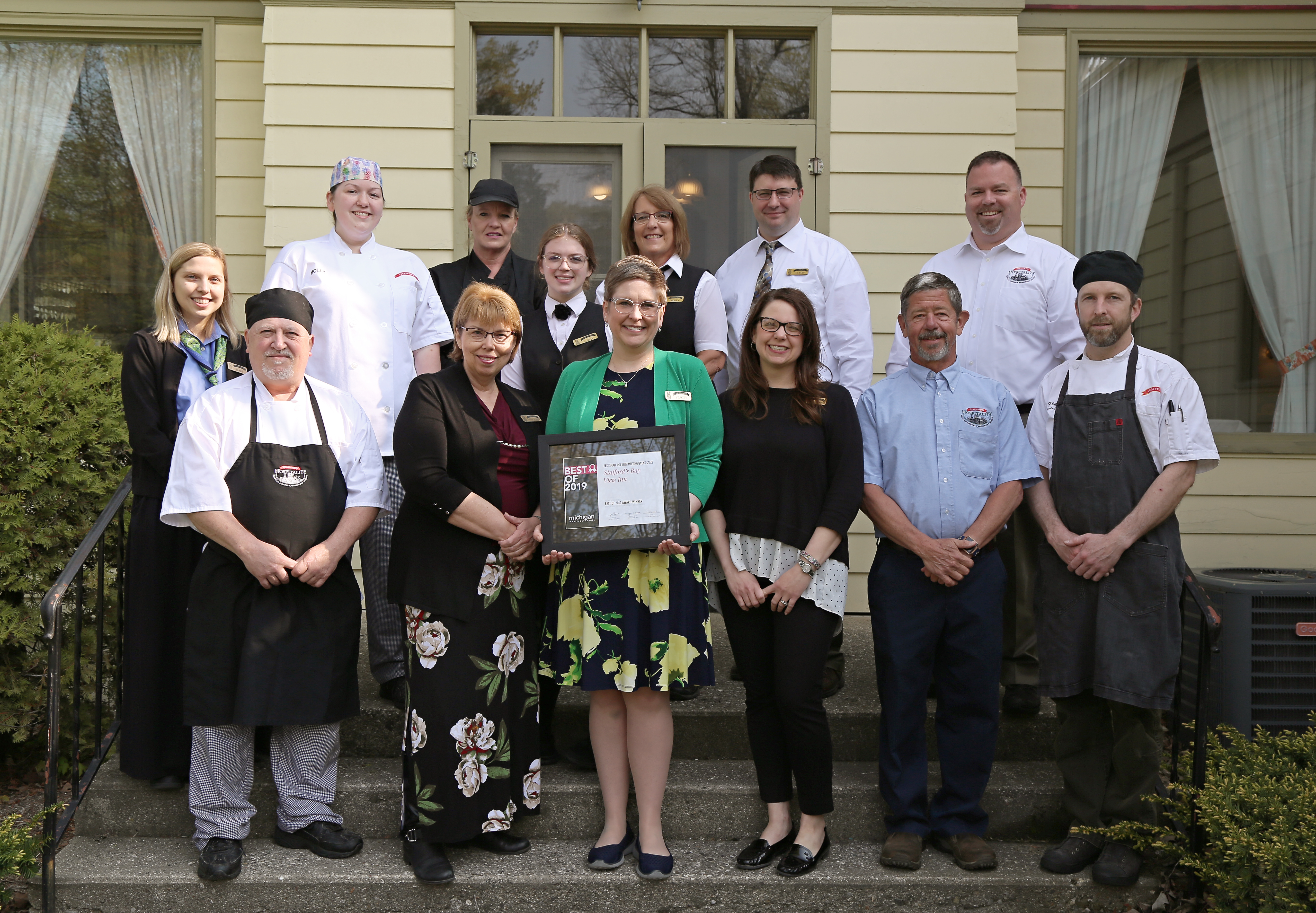 Kitchen staff standing in front of the hotel holding an award 