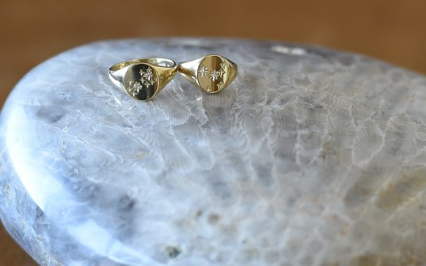 two gold rings with small diamonds on a small side table 