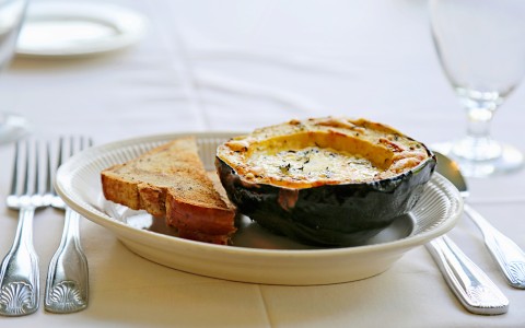acorn squash on a white plate with silverware on the side
