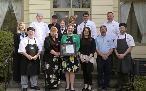 Kitchen staff standing in front of the hotel holding an award 