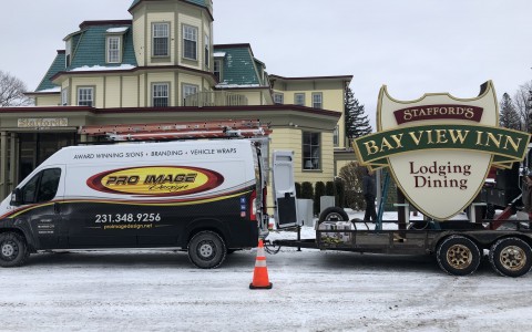 Van towing a large new sign for Bay View inn