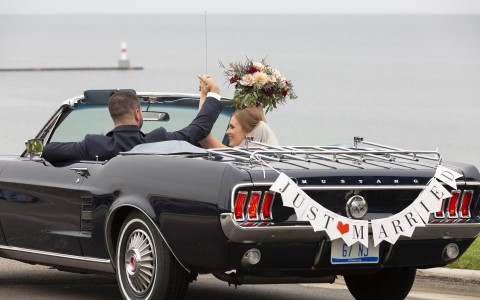bride and groom driving off after their wedding black convertible 