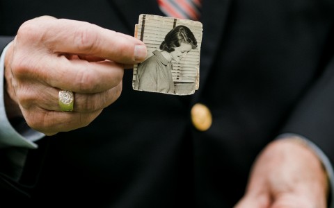 Man holding a older black and white photograph of a woman 