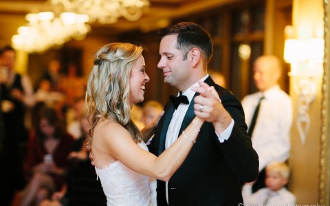 bride and groom dancing in the ballroom with guest observing in the background 