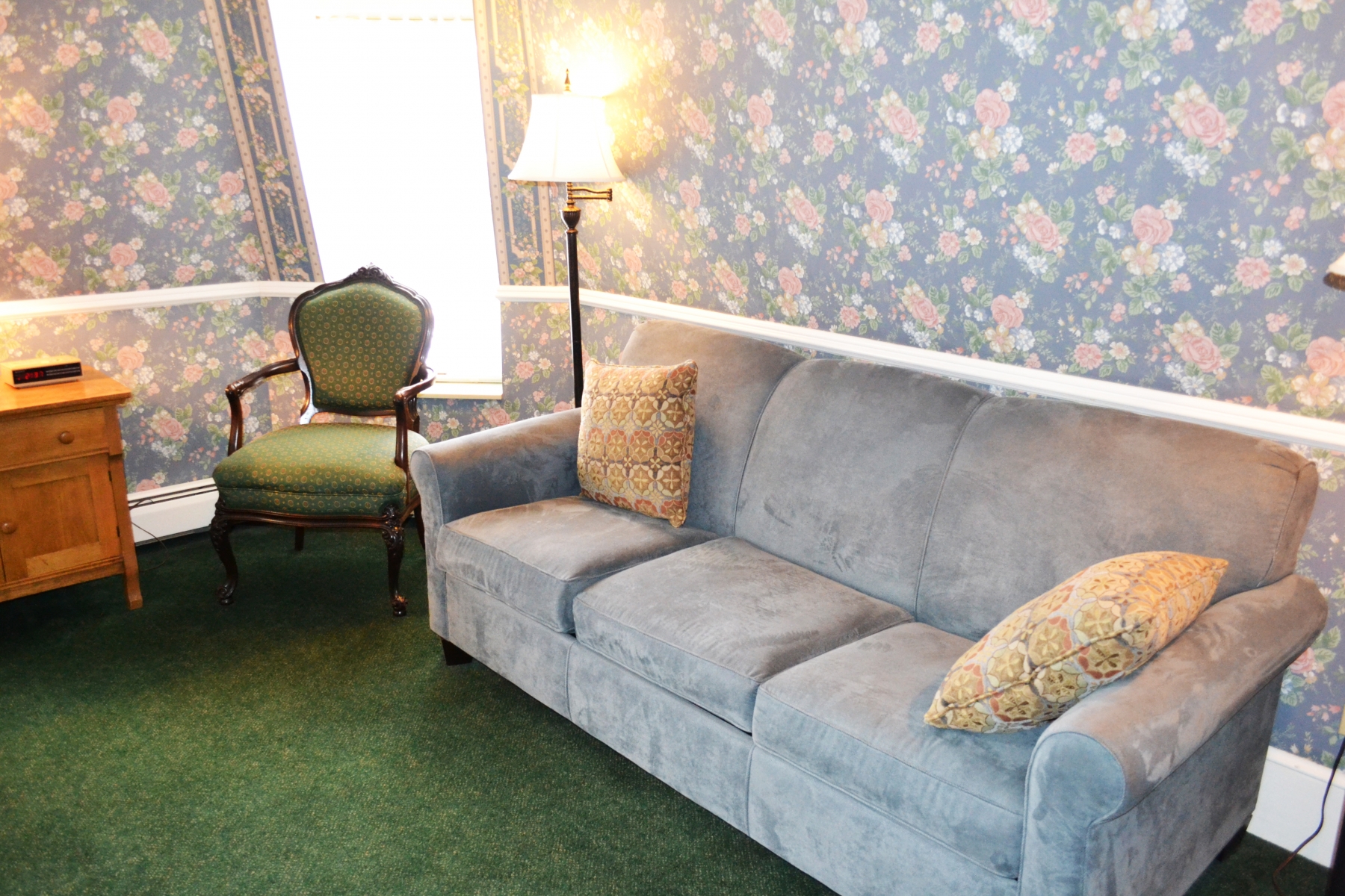 hotel room with floral wallpaper and blue couch 