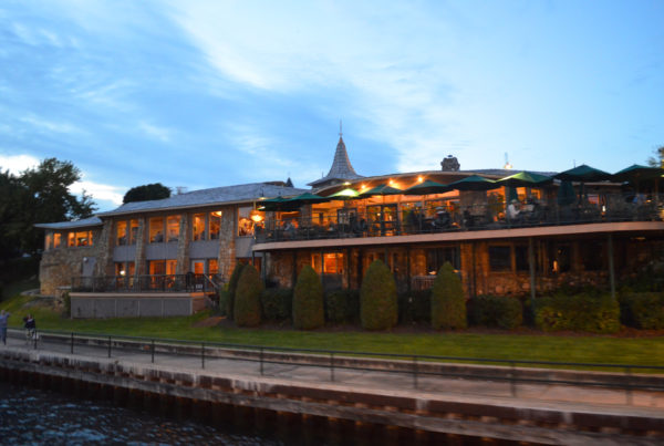 exterior of hotel on the water with green trees and landscaping around the building 