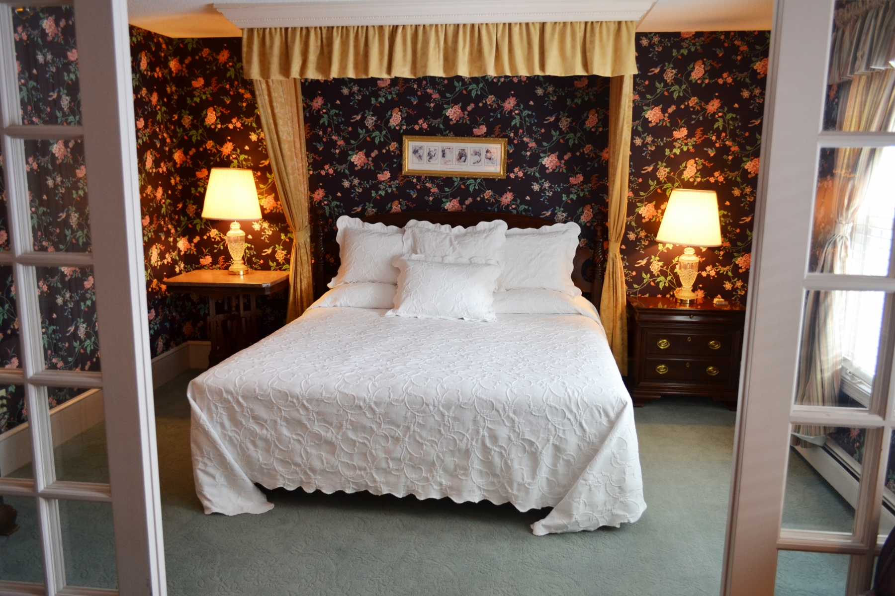 hotel room with floral wallpaper and white bedding and side tables on either side of the bed