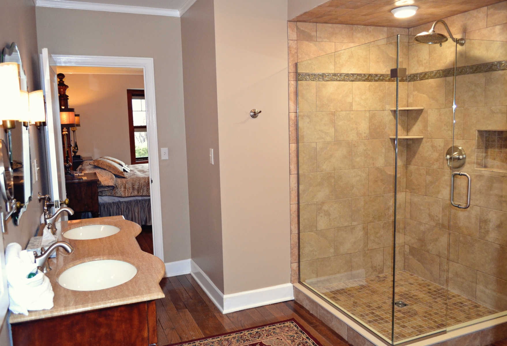 master bathroom with large walk in shower and double vanity with wood floors 