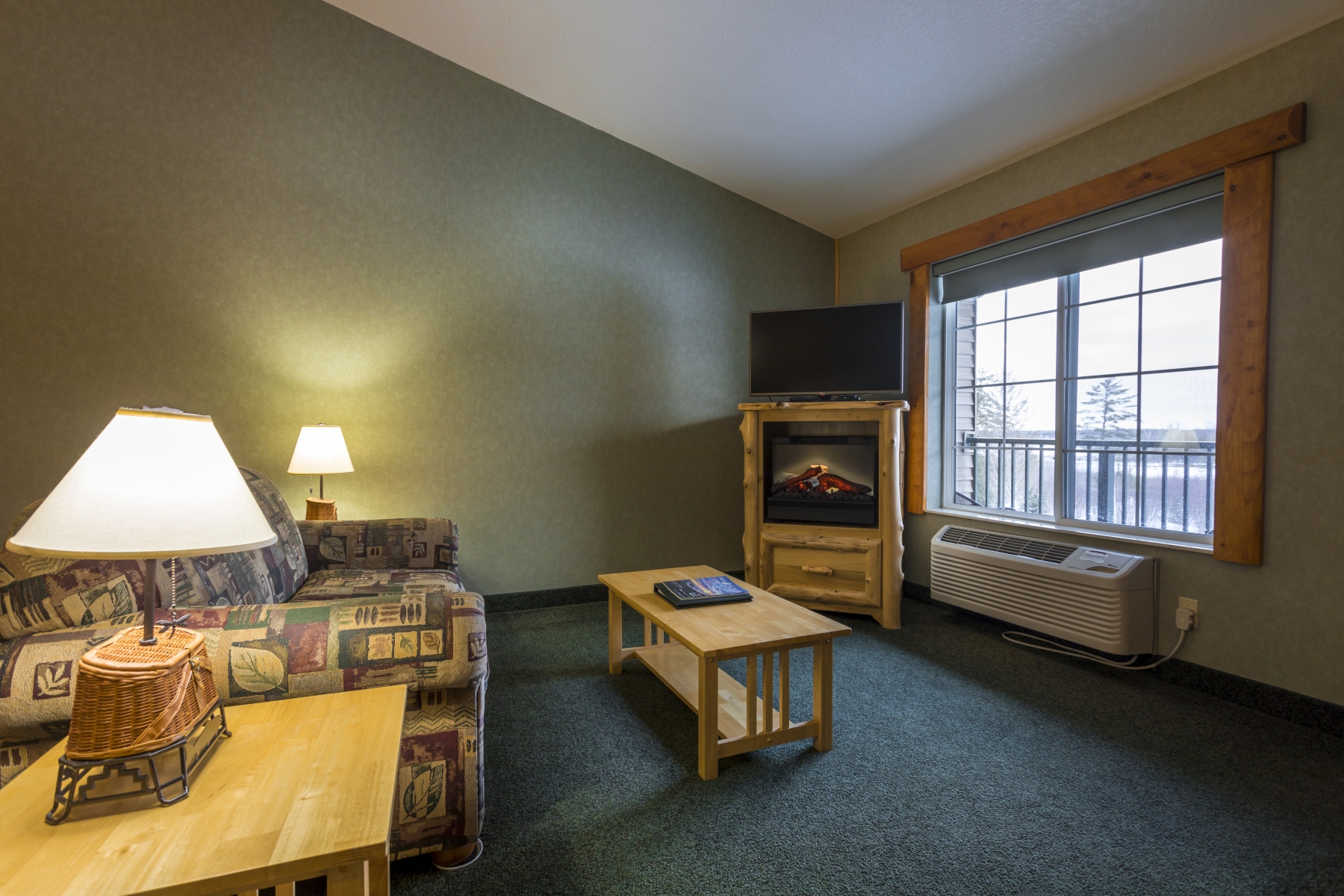 hotel room with couch and seating area with green walls and large window 