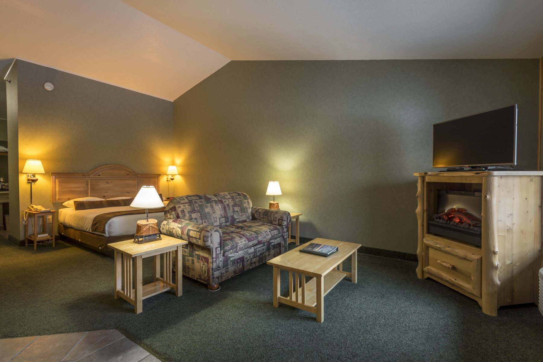 hotel room with couch and bed with green walls and fireplace 