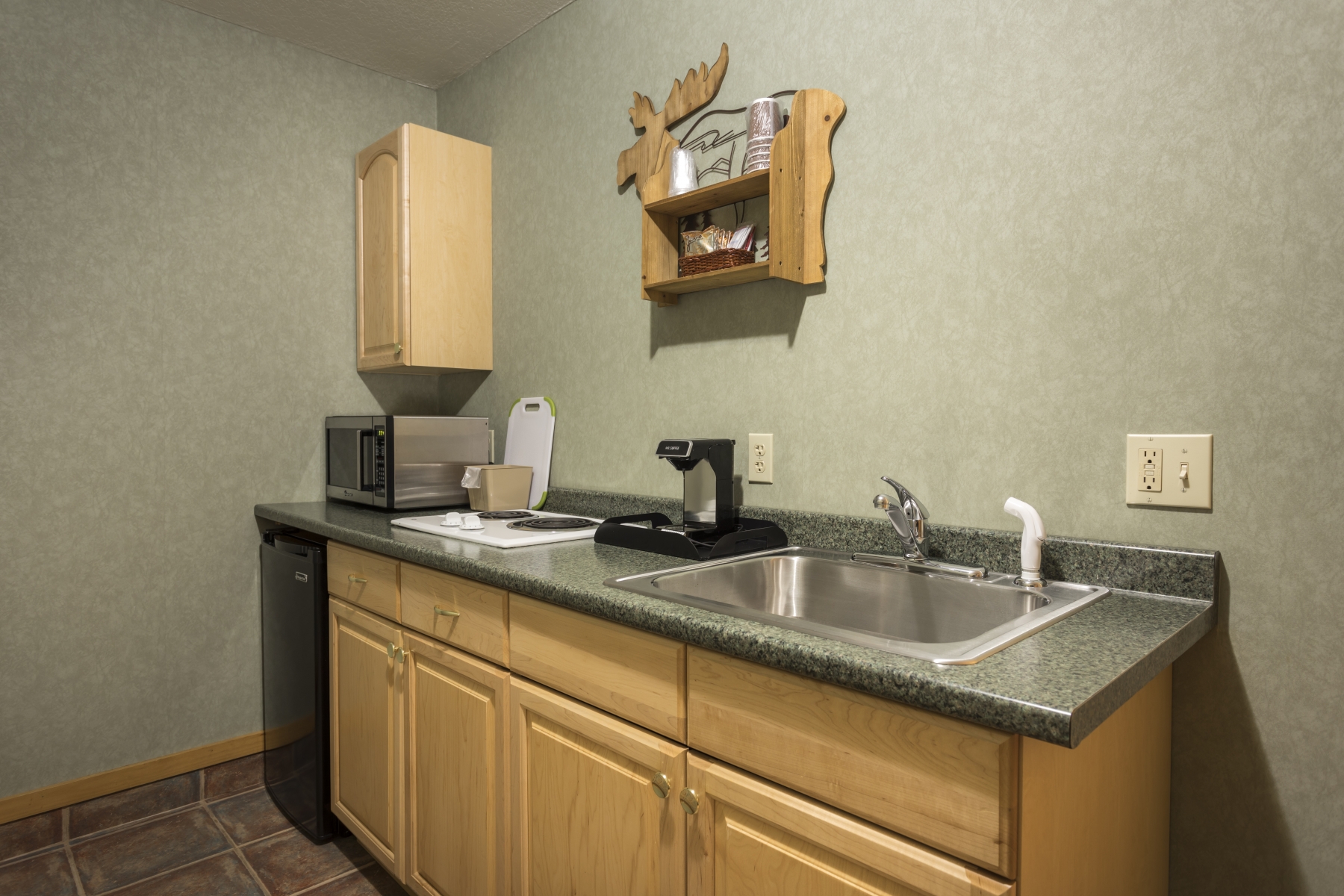 Kitchenette with sink, counter, mini fridge and cabinets 
